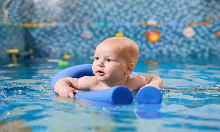 Havuzda yüzme destekleriyle su deneyimi yaşayan bebek